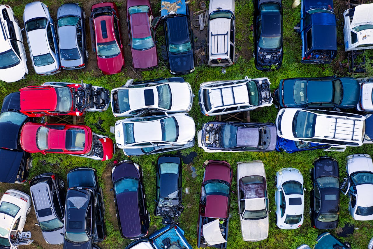 High-angle shot of various damaged cars in a junkyard surrounded by greenery.
