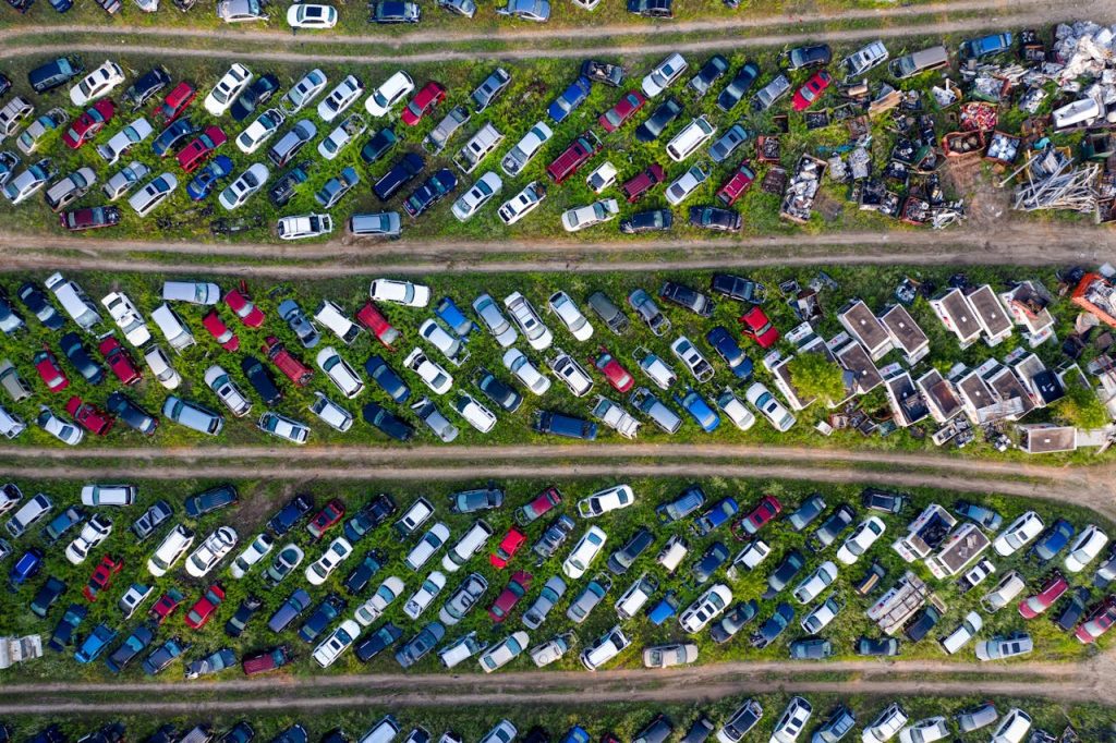 Top view of a busy scrapyard in Saint Charles filled with rows of abandoned vehicles and metal parts.