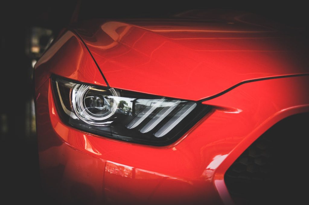 Detailed view of a red Ford Mustangs headlight showcasing sleek automotive design.